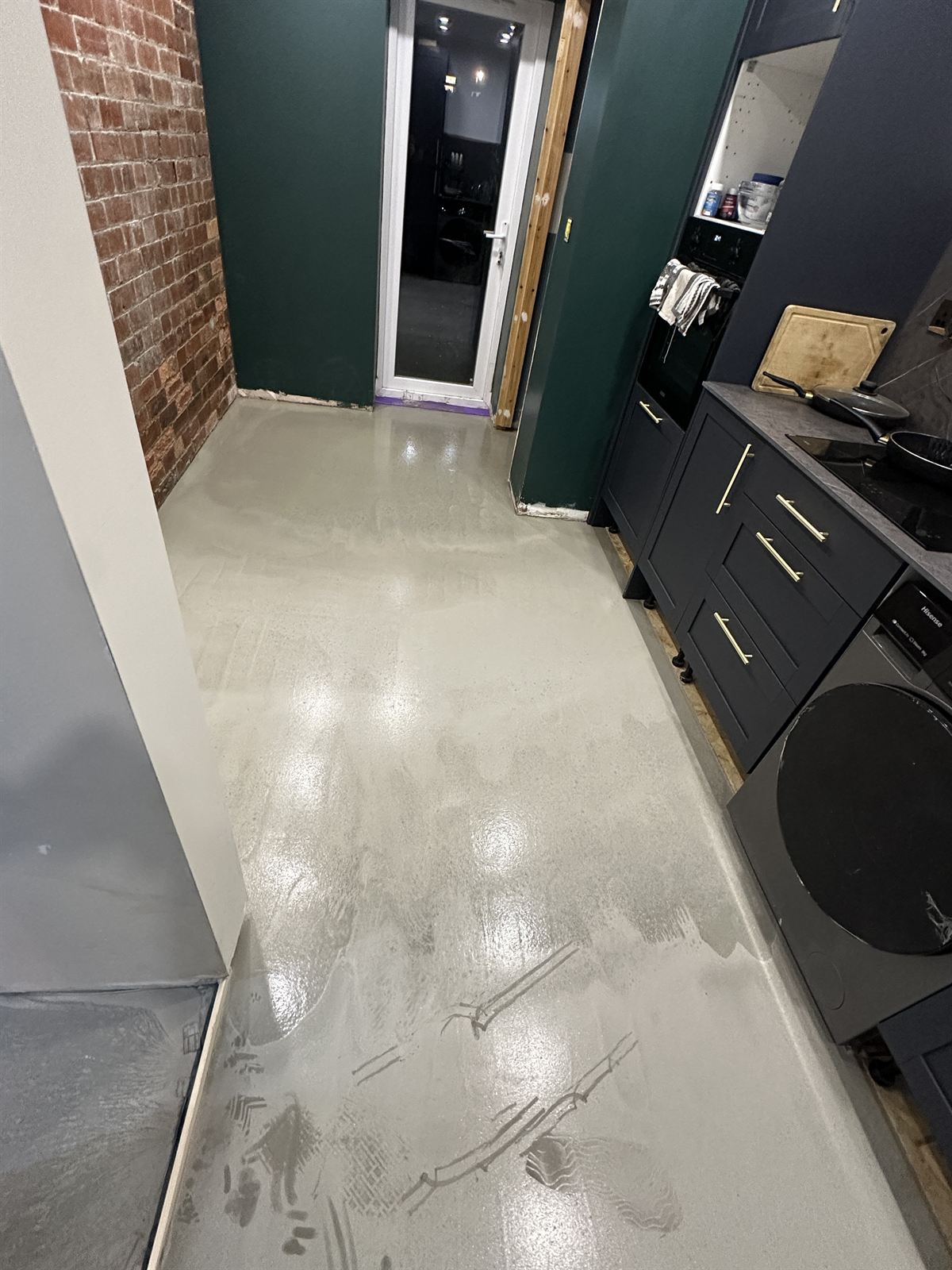 Dark green kitchen units with brick-effect floor