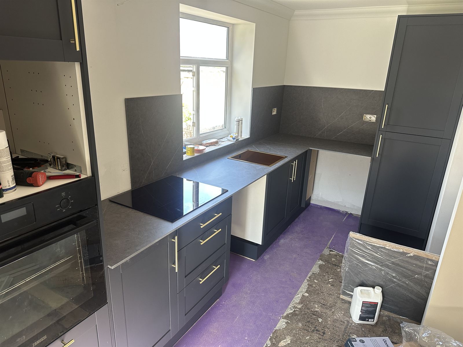 Full kitchen fitout with navy shaker units and stone worktops
