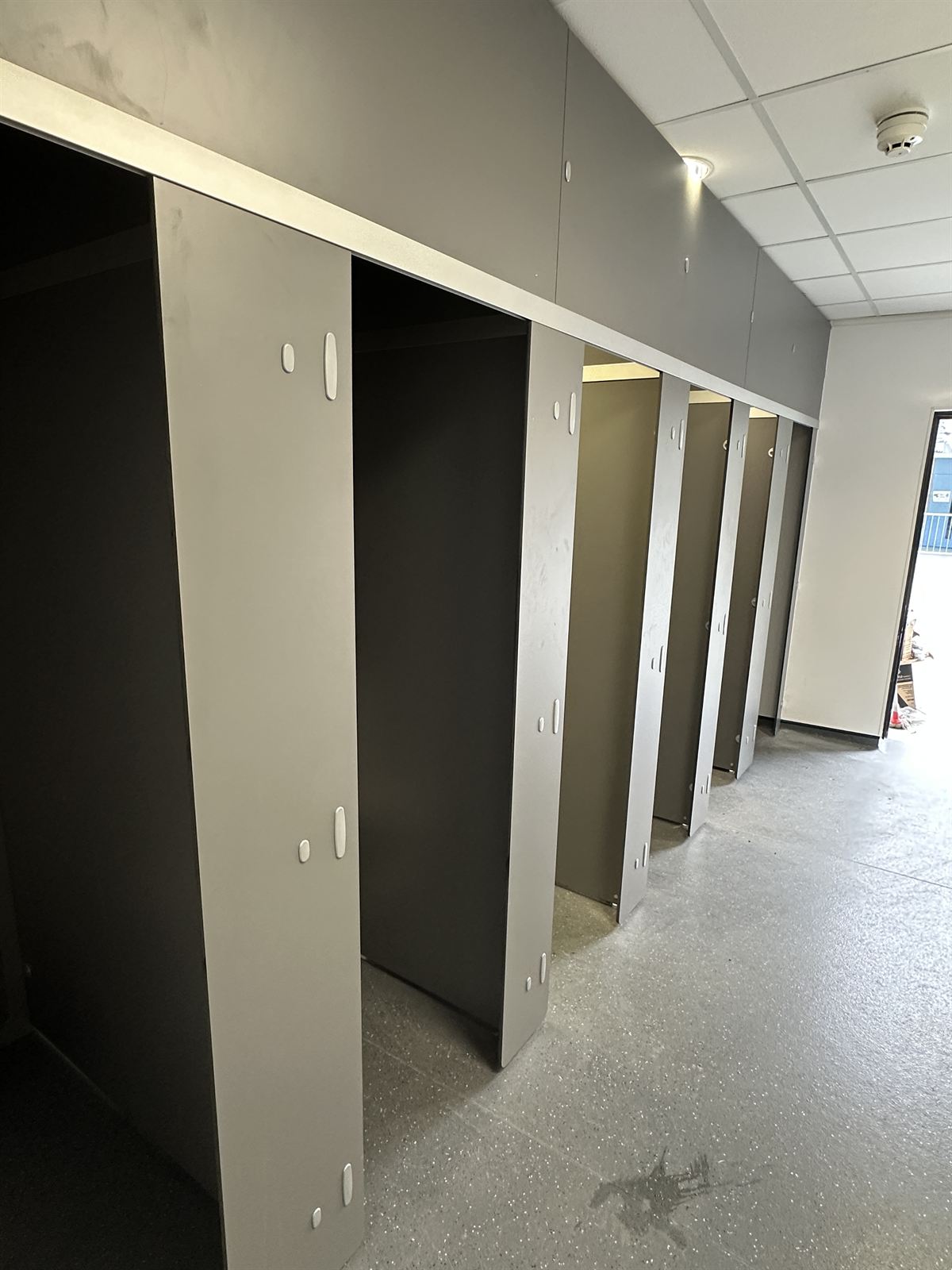 Row of grey toilet cubicles during commercial fit-out